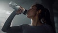 Sportswoman drinking water from sports bottle. Girl holding bottle in hand Royalty Free Stock Photo