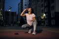 The sportswoman drinks water against the background of tall buildings. Fitness woman resting and rehydrating her body after