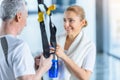 Sportswoman holding sport bottle and senior sportsman with resistance band talking