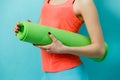 Sportswoman holding twisted fitness mat