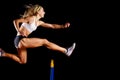 Sportswoman jumping over hurdle on sprint race