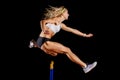 Sportswoman jumping over hurdle on sprint race