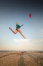 Sportswoman kitesurfer jumps with her kite on the beach. Free flight over land with a kite Royalty Free Stock Photo