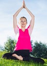 Sportswoman in pink T-shirt is sitting and doing meditation