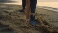 Sportswoman stretching reaching hand to leg outdoor. Girl doing warm-up on sand.