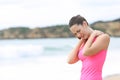 Sportswoman suffering neck ache on the beach