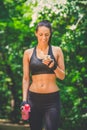 Sportswoman walking in nature and holding smartphone. Royalty Free Stock Photo