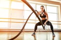 Sportswoman working out with battle ropes at gym