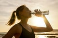 sporty woman drinking water from bottle after outdoor fitness workout at sunset Royalty Free Stock Photo