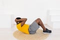 Sporty African American male doing home training and exercising doing sit-ups abs exercises crunches in headphones Royalty Free Stock Photo