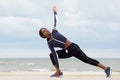 Sporty african american woman stretching muscles at the beach