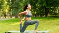 Sporty Asian girl doing yoga stretching exercises on mat at summer park Royalty Free Stock Photo