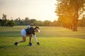 Sporty asian golfer woman putting golf ball on tee with club in golf course on sunny day for healthy sport. Royalty Free Stock Photo