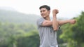 Sporty asian man stretching his arm, warming up before morning workout at the nature park. Healthy lifestyle, workout Royalty Free Stock Photo