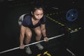 A sporty asian woman prepares to do conventional barbell deadlifts