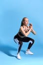 Sporty athletic beautiful woman in sneakers and tracksuit squatting in gym