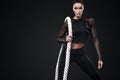 Sporty beautiful woman with battle rope makes fitness exercising at black background to stay fit