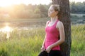 Sporty young woman leaning against a tree doing meditation and yoga exercises in nature Royalty Free Stock Photo
