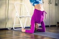 Sporty beautiful young woman practicing yoga, doing variation of Bridge Pose on elbows with chair agaainst wall Royalty Free Stock Photo