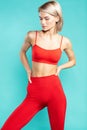 Sporty beauty. Young and sexy blonde woman in red sportswear looking away while standing against blue background. Sport