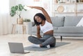 Sporty black girl exercising at home, using laptop Royalty Free Stock Photo