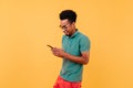 Sporty black man looking at phone screen and smiling. Portrait of joyful guy in green t-shirt texti Royalty Free Stock Photo