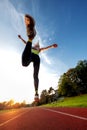 Sporty blond girl running in the summer sunset and jumping over camera, view from below Royalty Free Stock Photo