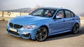 Sporty blue German bmw m3 sedan on a winding mountain road.