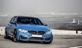 Sporty blue German bmw m3 sedan on a winding mountain road.