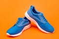 sporty blue sneakers pair on orange background, jogging shoes