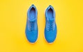 sporty blue sneakers pair on yellow background, footwear