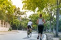 Sporty Caucasian woman running on the road in the Asian city park with green tree row in early morning