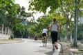 Sporty Caucasian woman running on the road in the Asian city park with green tree row in early morning