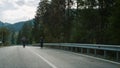 Sporty couple cycling forest on highway road. Travelers riding bike in mountains Royalty Free Stock Photo