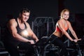 Sporty couple exercising at the fitness the exercise bike on a dark gym. Royalty Free Stock Photo