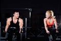 Sporty couple exercising at the fitness the exercise bike on a dark gym. Royalty Free Stock Photo