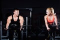 Sporty couple exercising at the fitness the exercise bike on a dark gym. Royalty Free Stock Photo