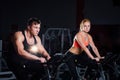 Sporty couple exercising at the fitness the exercise bike on a dark gym. Royalty Free Stock Photo