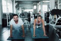 Sporty Couple are Push-Up Exercising in Fitness Gym., Portrait of Young Pretty Woman is Working Out Against on Sport Bodybuilding