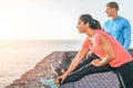 Sporty couple stretching legs in front of ocean at sunset - young people training and making legs exercises outdoor Royalty Free Stock Photo