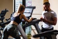 Sporty couple workout cardio exercise gym. Sportive couple in gym. Personal trainer fitness instructor helping woman Royalty Free Stock Photo