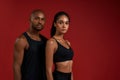 Sporty couple. Young african fitness couple in sportswear looking at camera while standing against red background Royalty Free Stock Photo