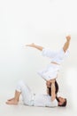 Sporty family on white background. Middle-aged man lying on floor holding young woman stretching legs, practicing yoga. Royalty Free Stock Photo