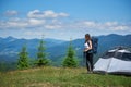 Woman hiker near camping in the mountains with backpack and trekking sticks in the morning Royalty Free Stock Photo