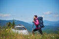 Woman tourist near camping in the mountains with backpack and trekking sticks in the morning Royalty Free Stock Photo