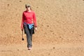 Sporty female hiking desert wasteland across volcanic crater.