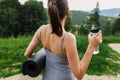 Sporty female holding yoga mat and bottle of water at sunny mountain hills. Healthy outdoor workout Royalty Free Stock Photo