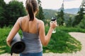 Sporty female holding yoga mat and bottle of water at sunny mountain hills. Healthy outdoor workout Royalty Free Stock Photo