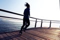 Female jogger morning exercise on seaside boardwalk during sunrise Royalty Free Stock Photo