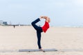 Sporty fit blond woman in red and dark blue sportswear working out outdoors on summer day, doing Natarajasana, Dancer Royalty Free Stock Photo